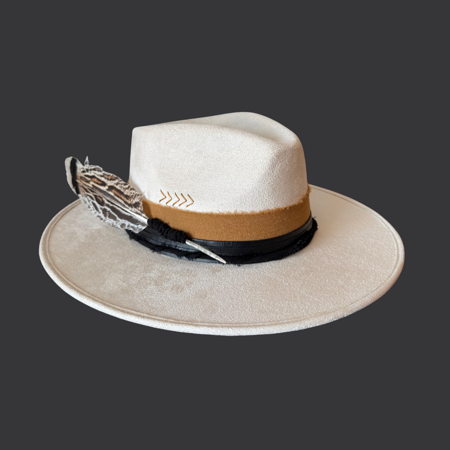 Left side view of ivory boho fedora with black leather band, burnt orange cotton wrap, and turkey feather