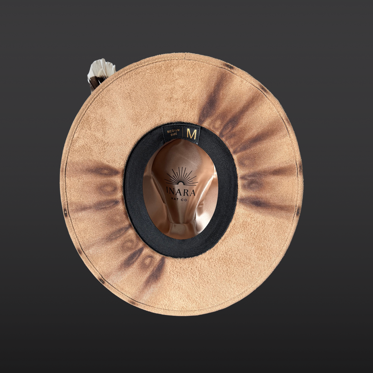 Torch burned details under the brim of a wide-brimmed camel-colored fedora featuring a dark brown leather band, turkey feather accent, agate stone, and hand-burned Seed of Life and Merkaba designs visible along the crown.