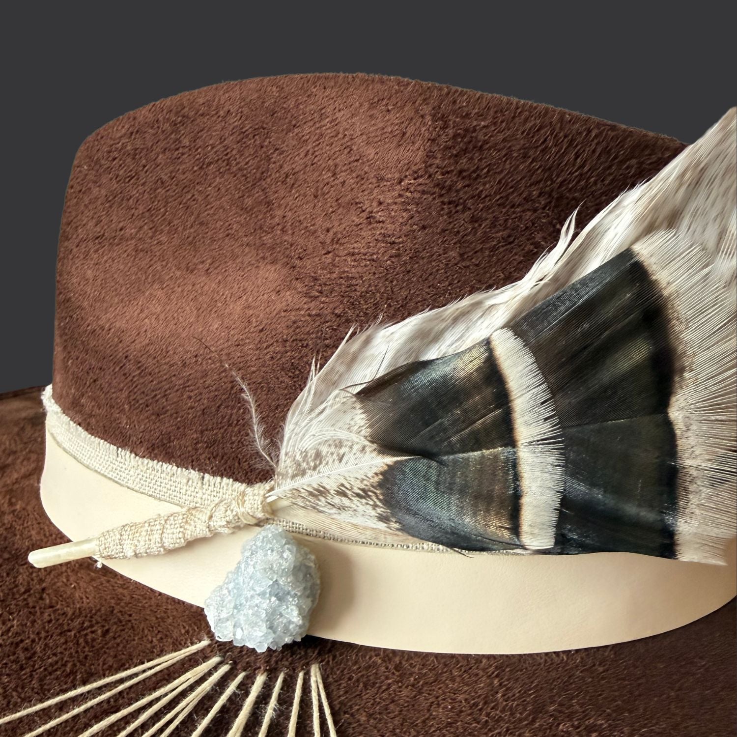 Brown wide brim fedora with celestite crystal and hand embroidered sunburst design / close up of feathers
