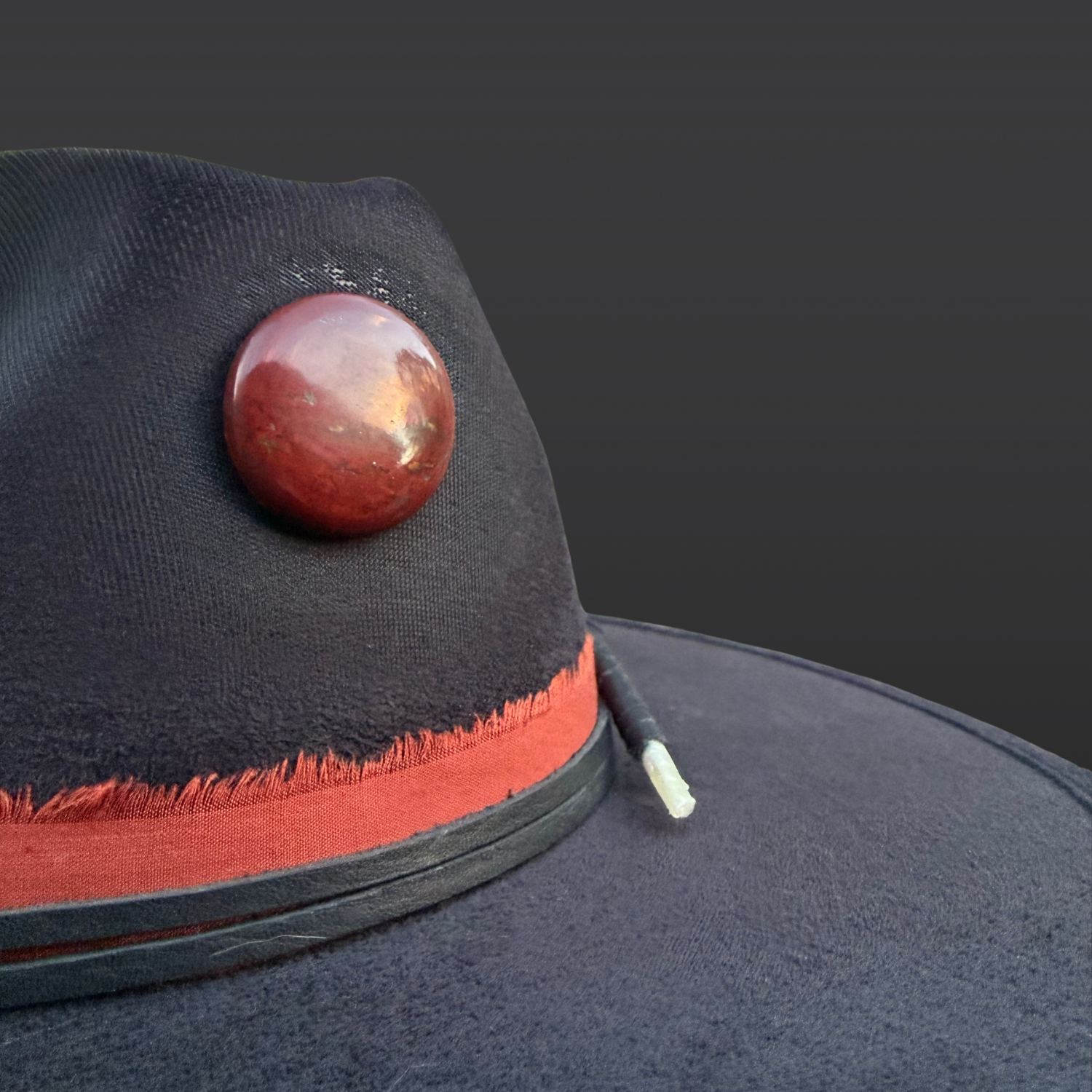 Black boho fedora hat with red jasper stone, hummingbird embroidery, and feather accent. Close up of red jasper by Inara Hat Co.