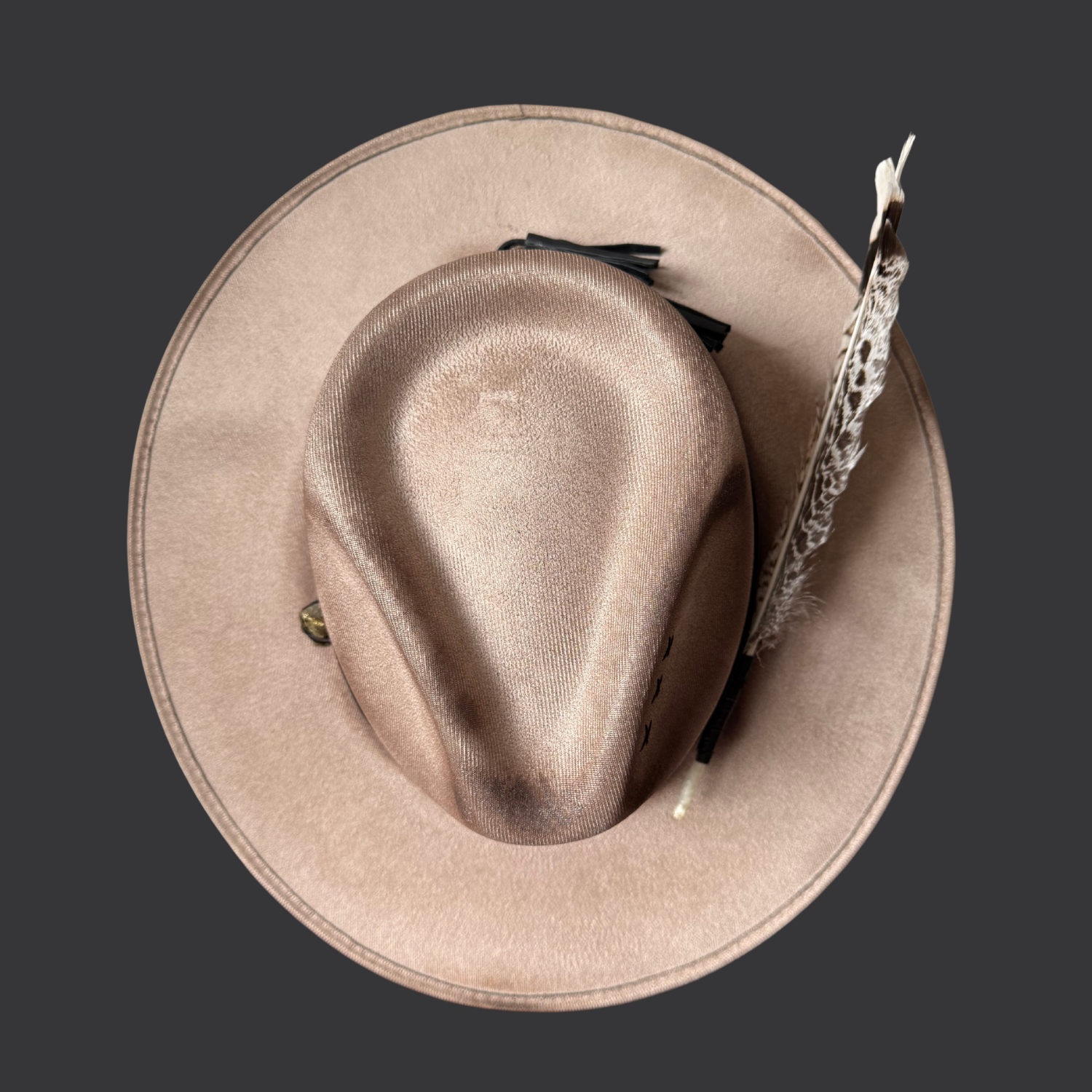 Top view of khaki wide-brim fedora hat with chalcopyrite crystal and black leather tassels