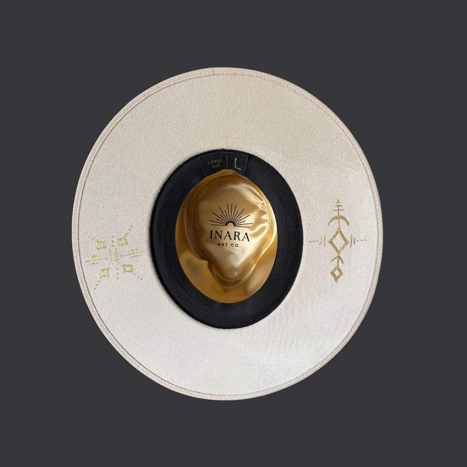 Ivory wide-brim fedora with gold hand-painted designs, white cotton band, and gold charm accents / under brim view