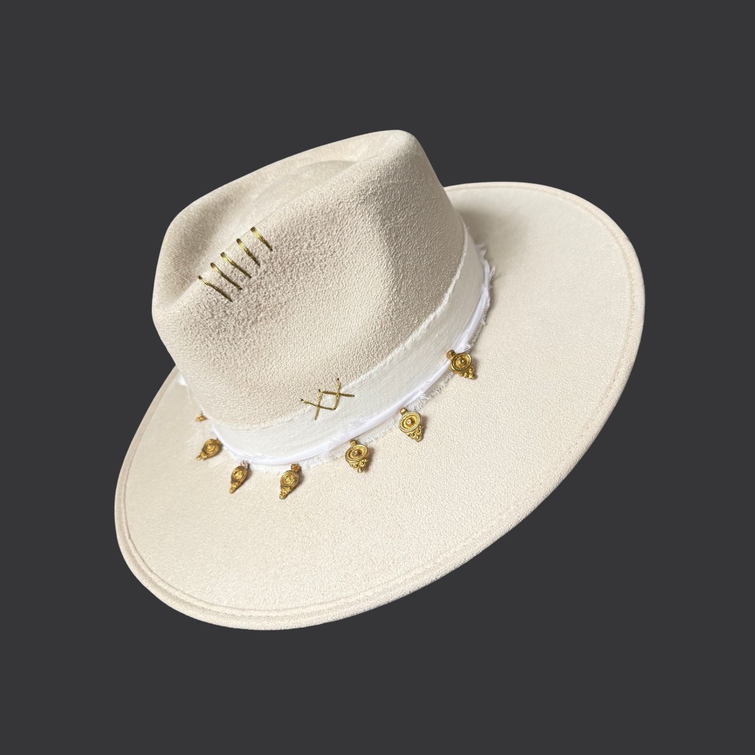 Ivory wide-brim fedora with gold hand-painted designs, white cotton band, and gold charm accents / left side view