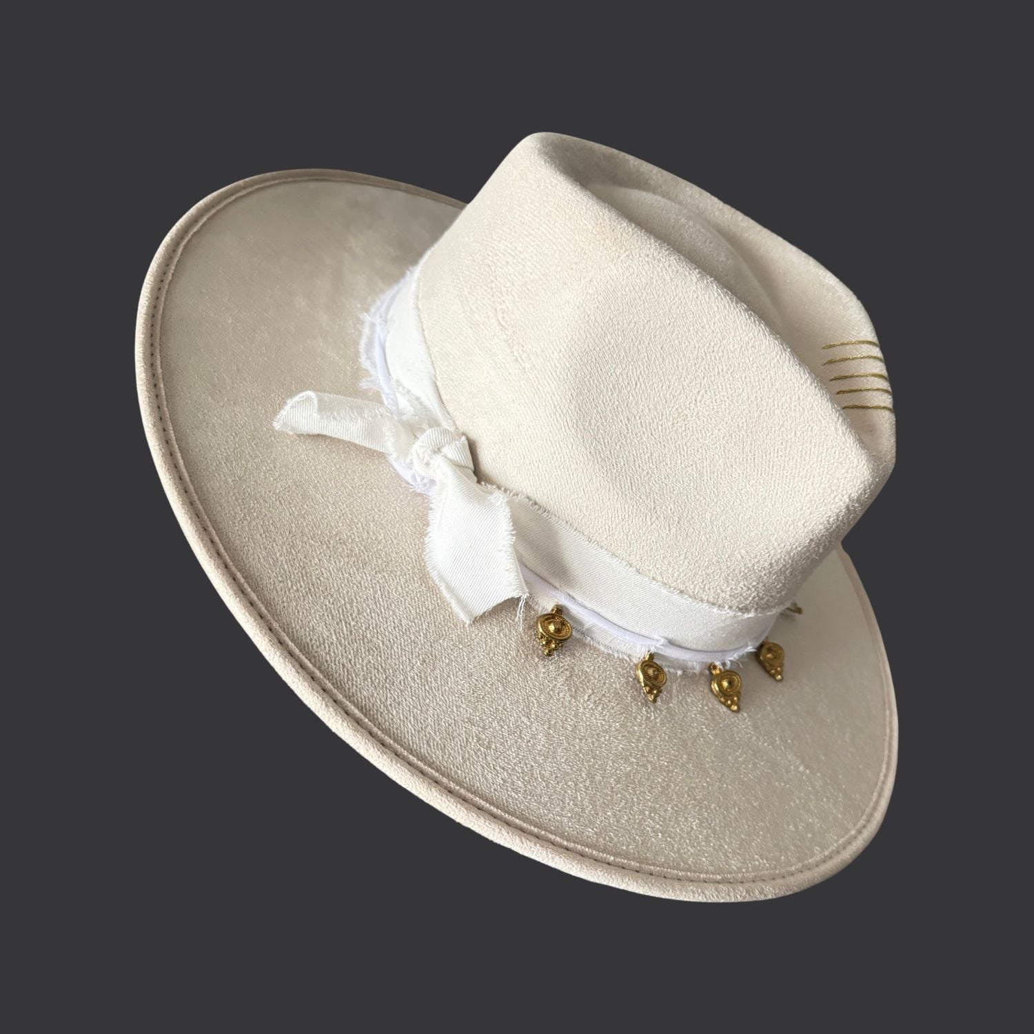 Ivory wide-brim fedora with gold hand-painted designs, white cotton band, and gold charm accents / left side view