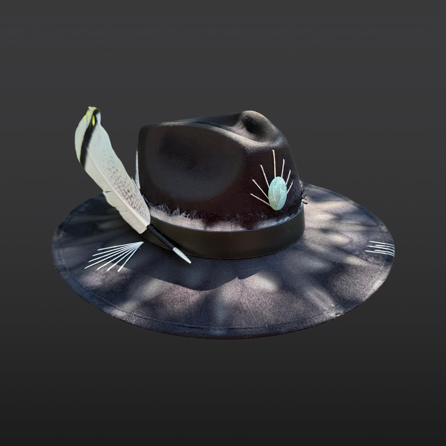 Left side view of Ocean Within black wide brim fedora with aquamarine stone, black leather band, aqua and turquoise cotton band, turkey feather, and hand embroidered accents by Inara Hat Co.