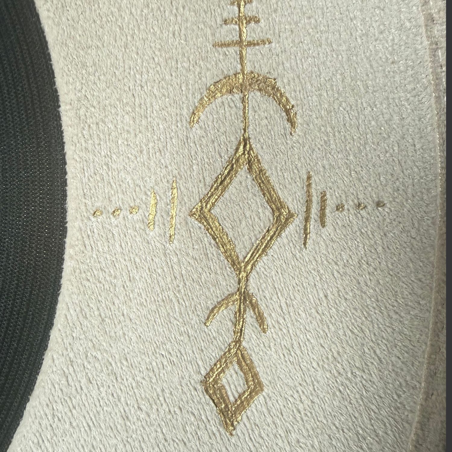 Ivory wide-brim fedora with gold hand-painted designs, white cotton band, and gold charm accents / close up of gold painted design 2
