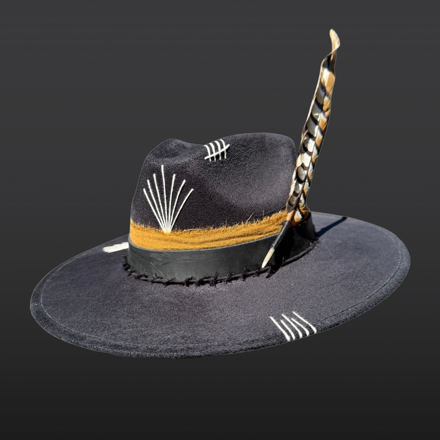 Wild & Free black wide brim fedora with white sunburst embroidery, black leather band, tobacco cotton band, and pheasant feather.