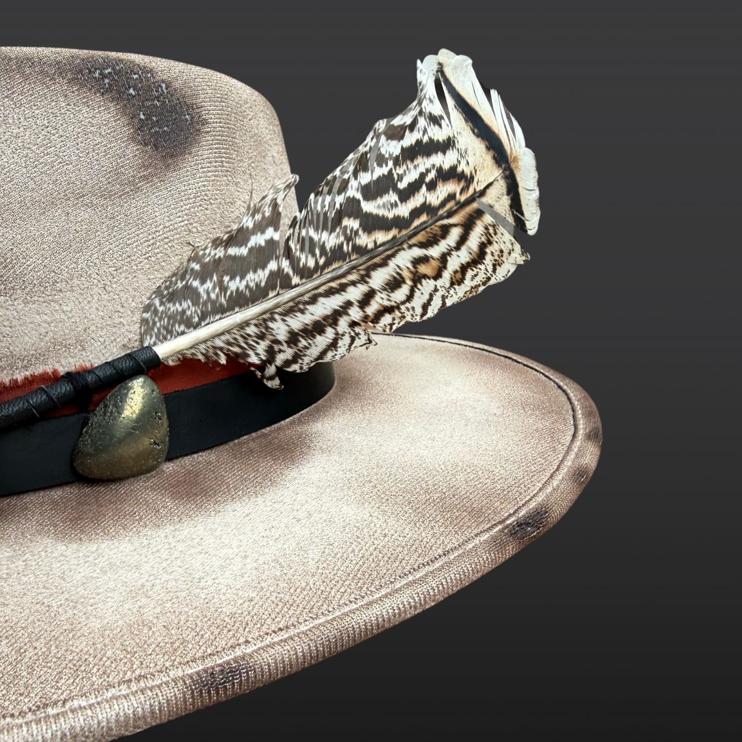 Close-up of pyrite crystal, and layered rust red and black leather band on Ember Guardian hat.