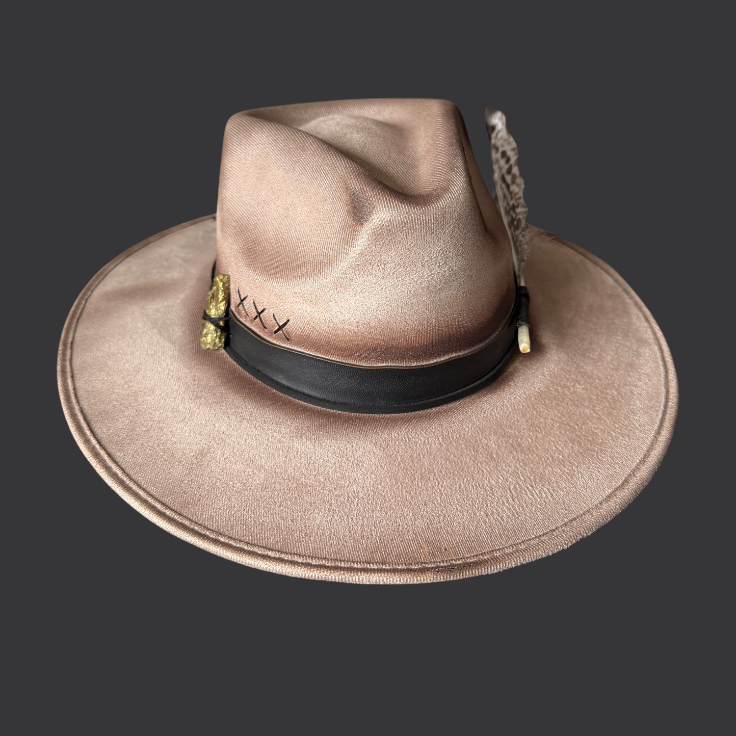 front view of khaki wide-brim fedora hat with chalcopyrite crystal and black leather tassels