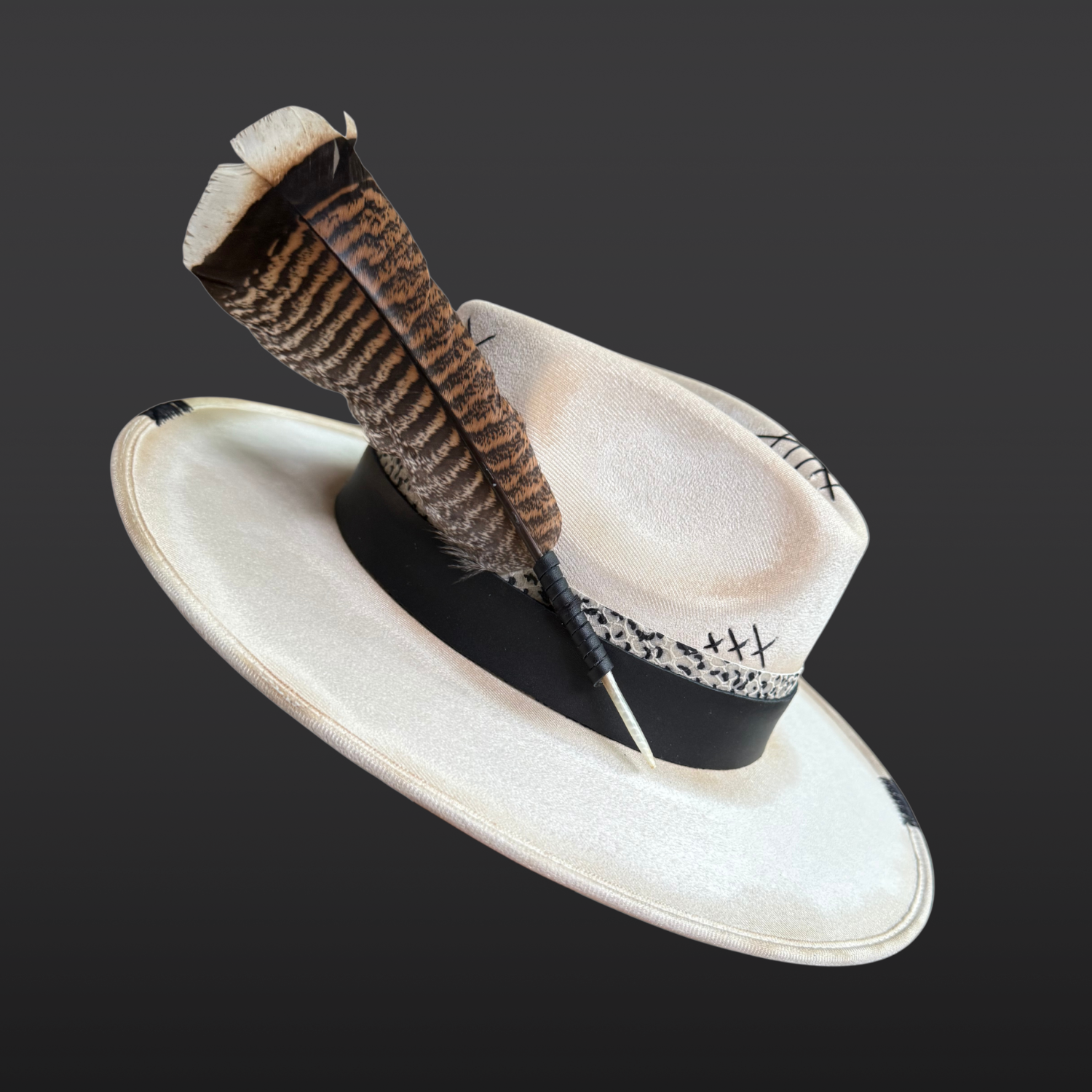 Angled left side view of Unbound ivory wide brim fedora hat featuring black embroidered details and a rugged hand-torched finish.