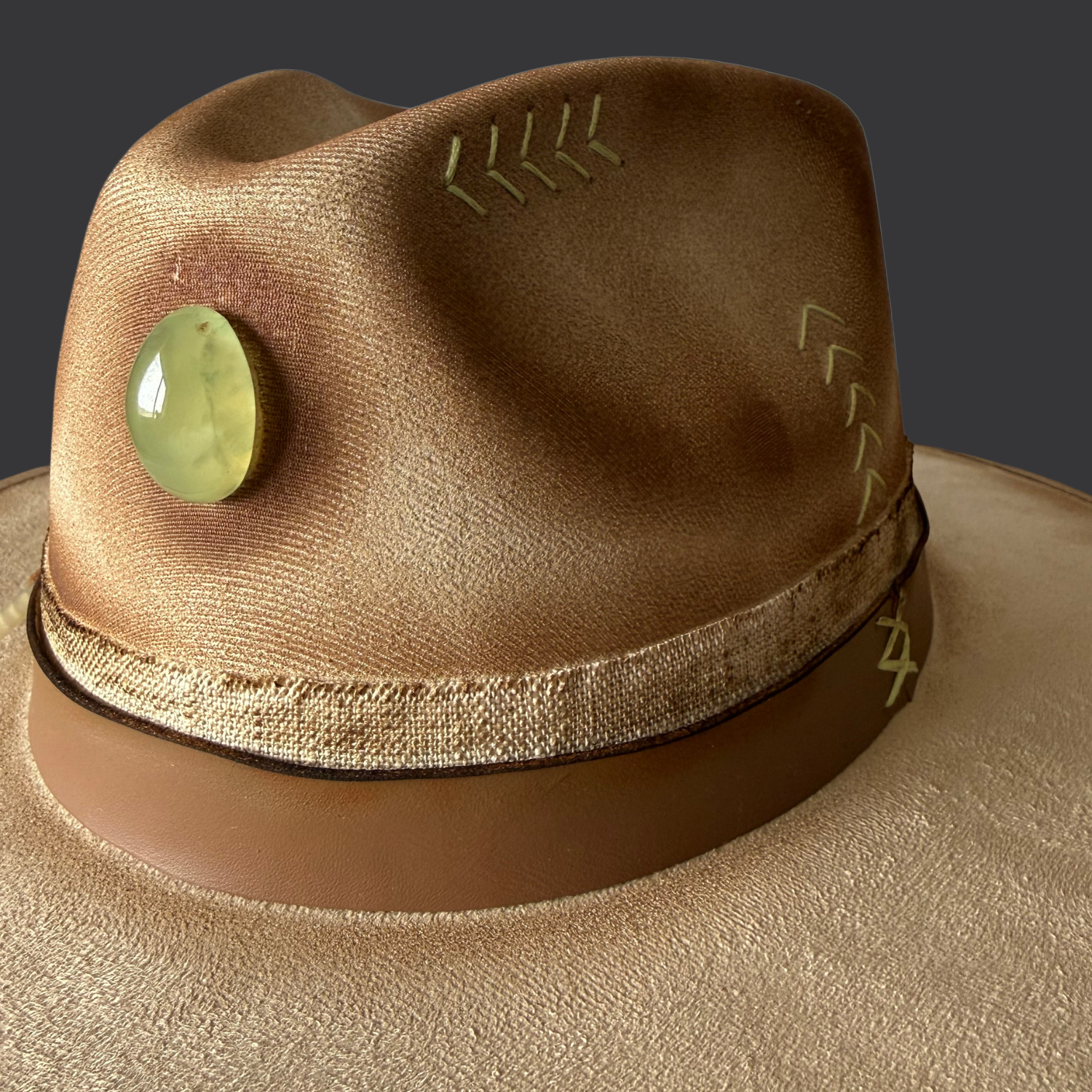 Close up of right side view of cream wide-brim hat showing hand-torched texture and embroidered “M B D” on crown
