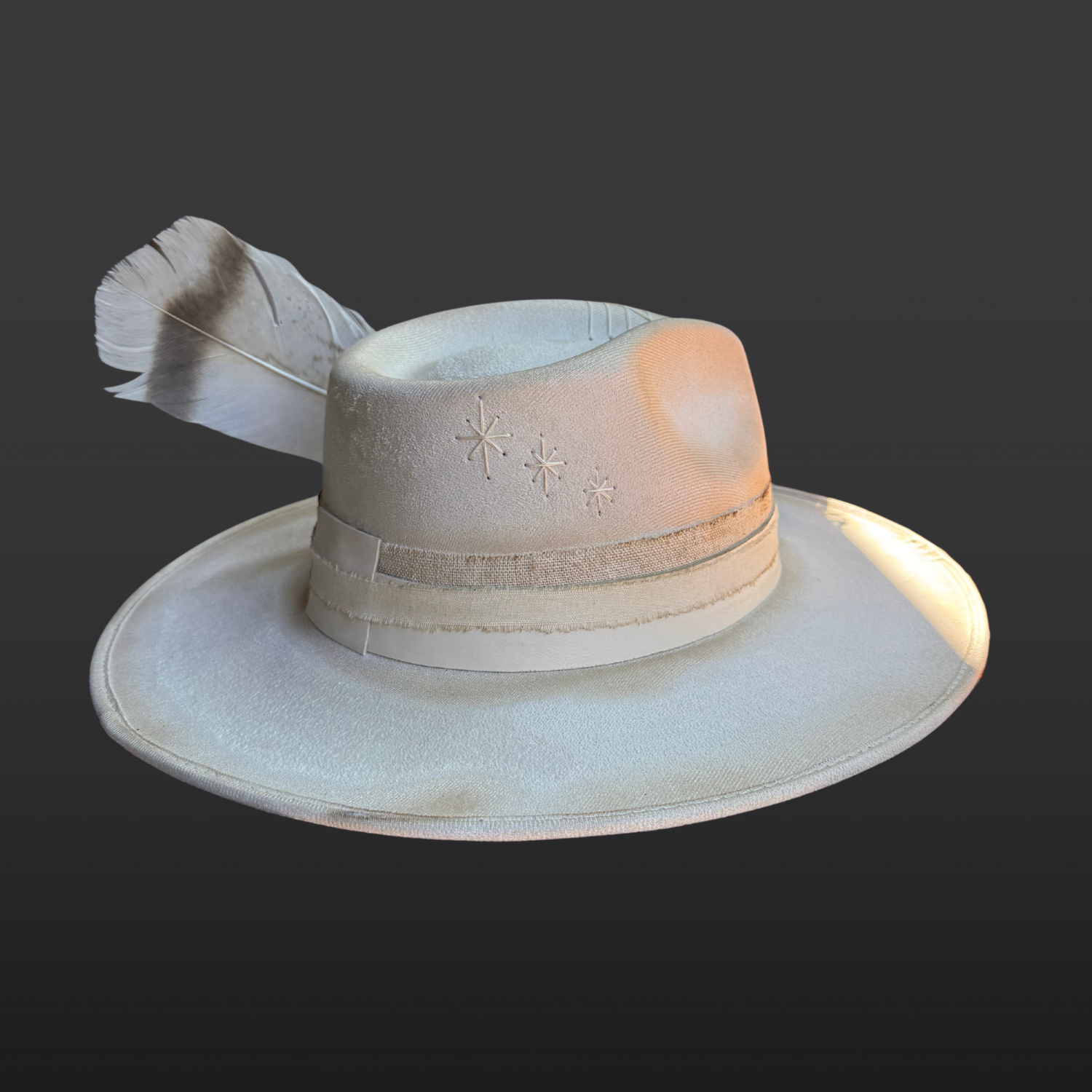 Side view of ivory wide brim fedora with blue lace agate crystal centerpiece, hand embroidered details, ivory leather band, and floral feather accents.