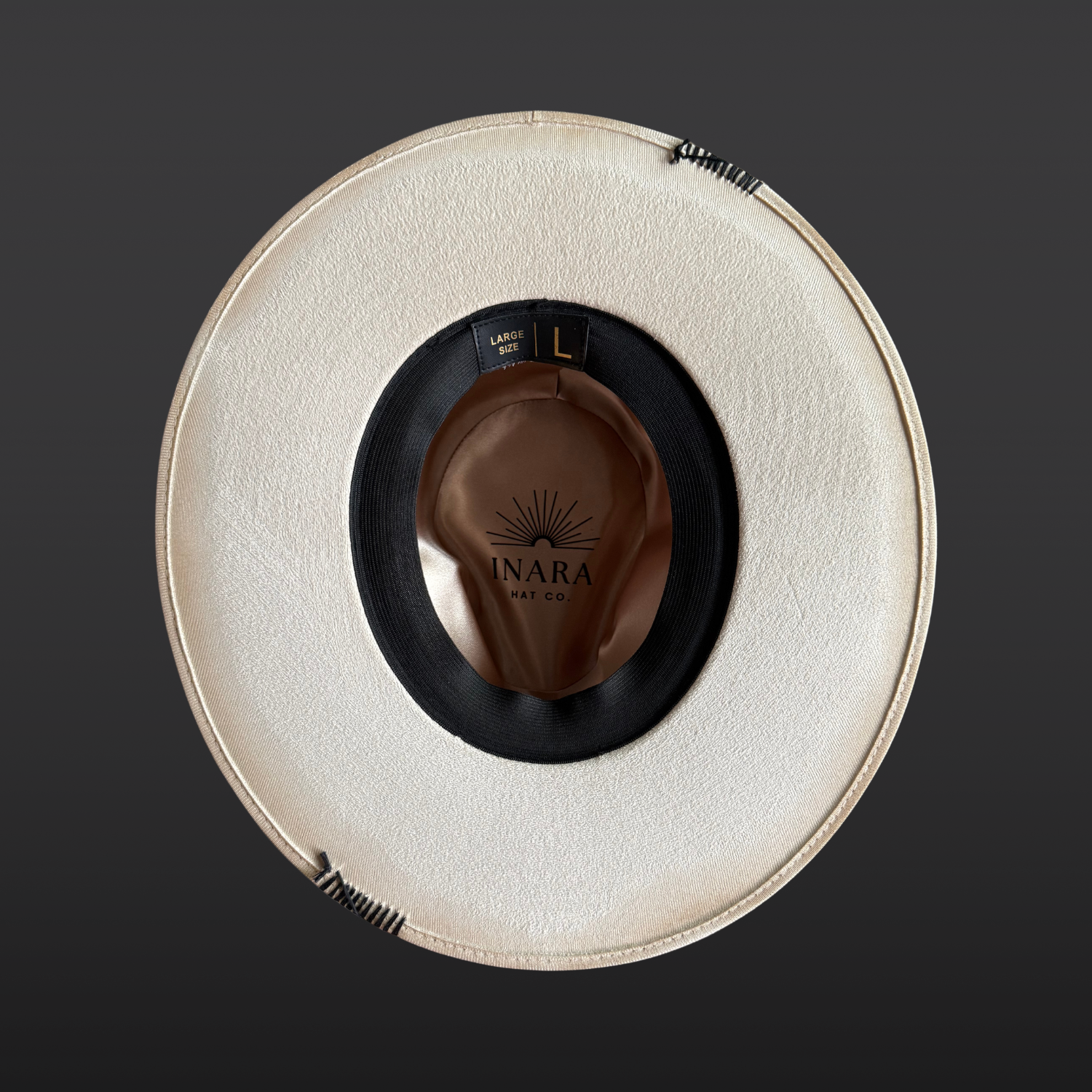 Under brim view of Unbound ivory wide brim fedora hat featuring black embroidered details and a rugged hand-torched finish.