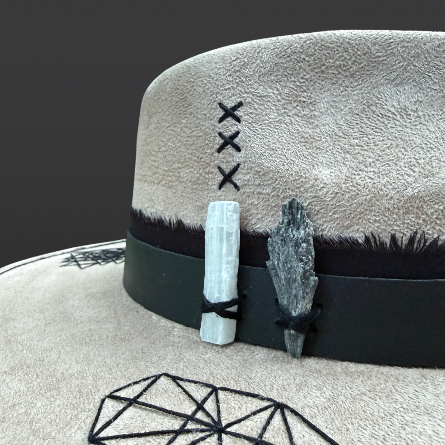 Close-up of black kyanite and selenite crystals attached to Rooted Light fedora with organic cotton and leather bands.
