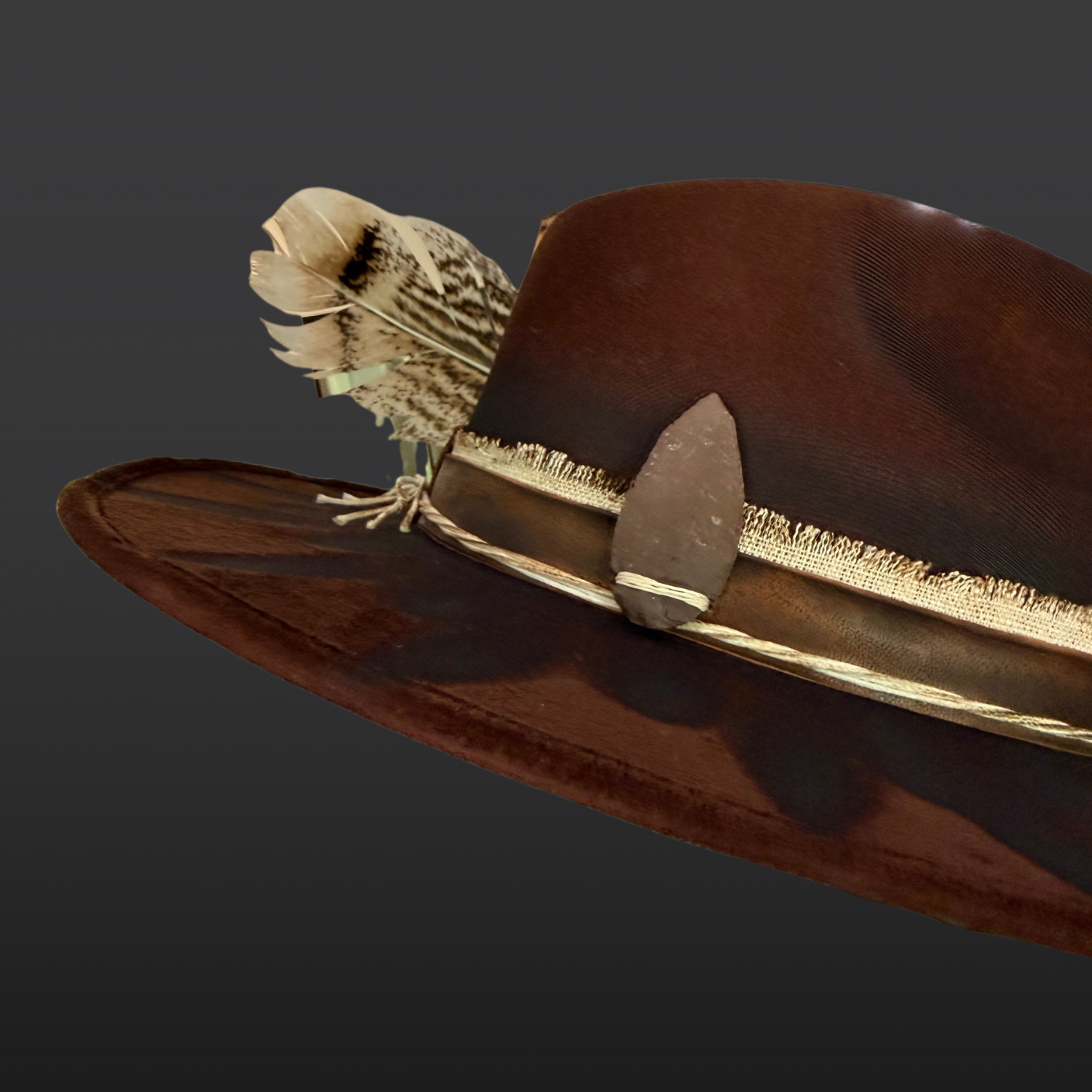 Close-Up of stone arrow on brown wide brim fedora hat inspired by ancient symbolism and guidance