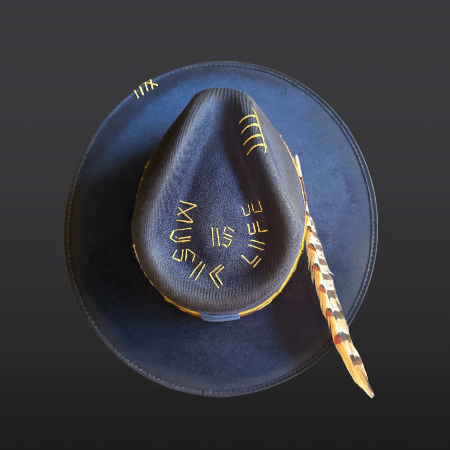 Close-up of the crown embroidery reading “Music Is Life” on a navy fedora hat.