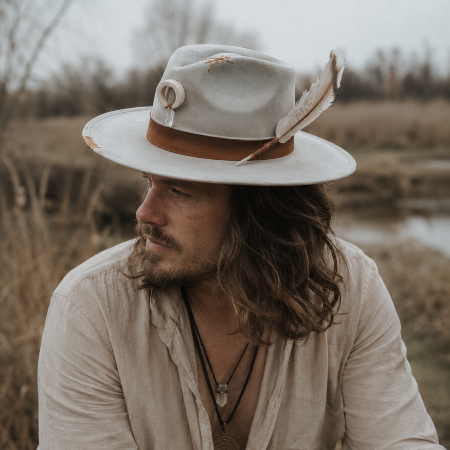 Boho man wearing the Way fFnder wide brim fedora hat ,one-of-a-kind grey fedora with hand-burned detailing and embroidered accents, IN NATURE