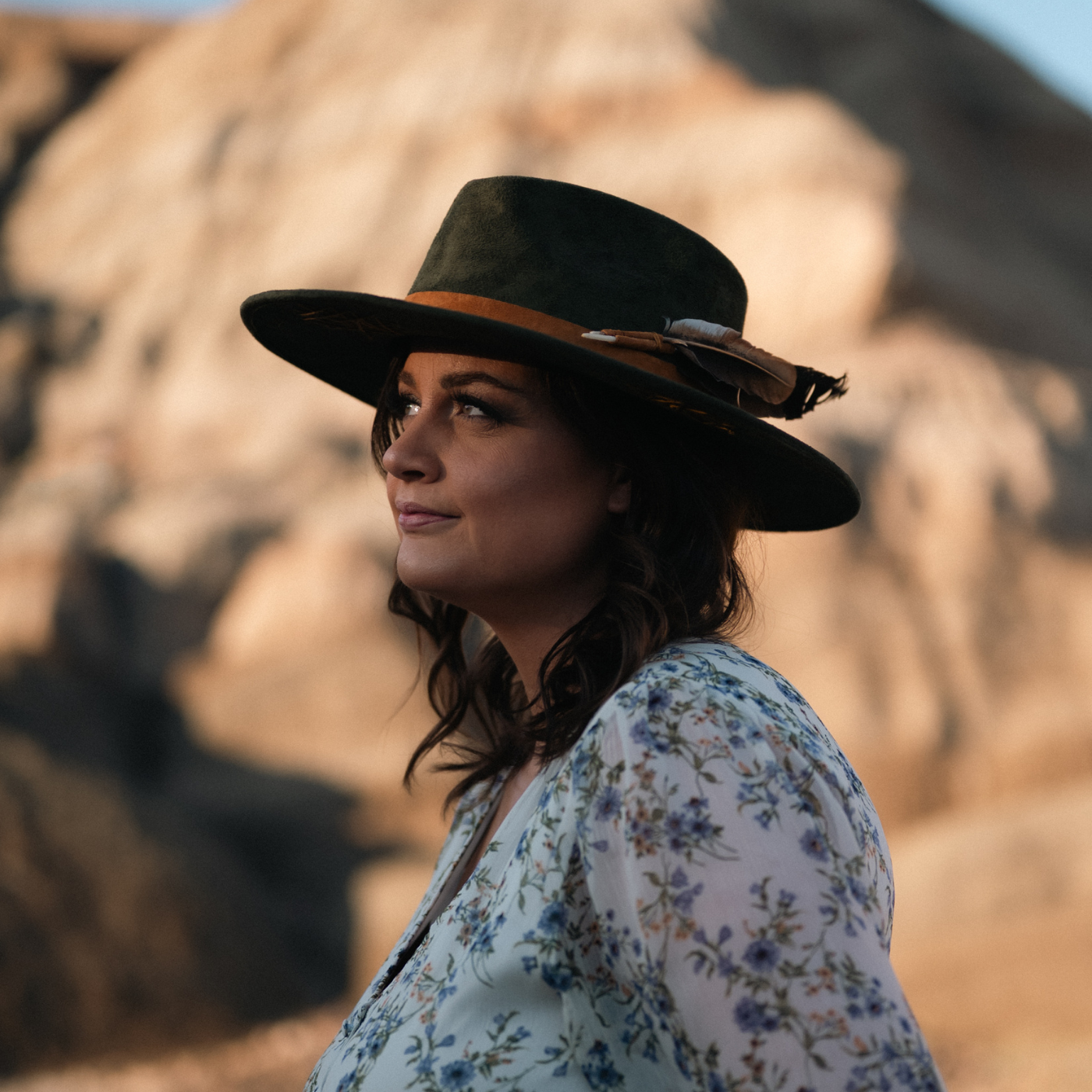 Close up of model wearing dark green wide-brim vegan suede fedora hat with Tree of Life and Sri Yantra embroidery and camel leather band