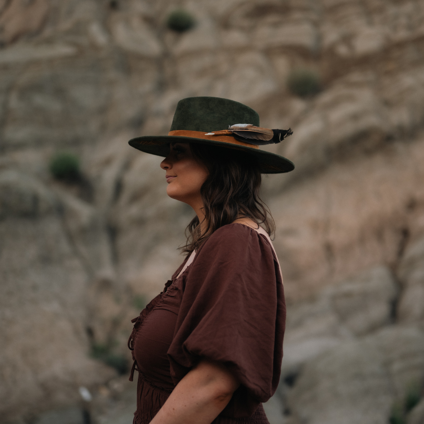 Model wearing dark green wide-brim vegan suede fedora hat with Tree of Life and Sri Yantra embroidery and camel leather band