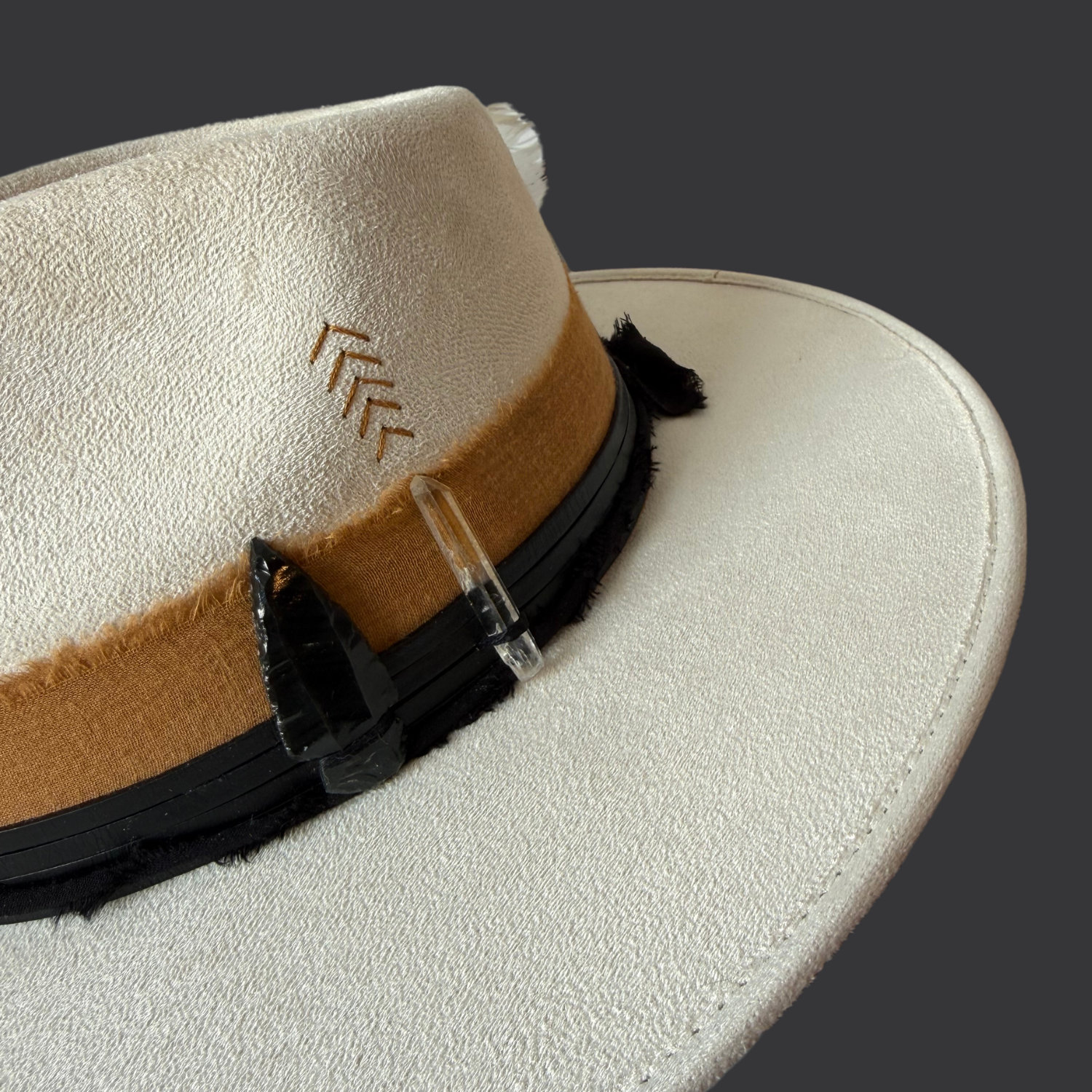 Close-up of Lemurian quartz and black obsidian arrow on ivory fedora hat