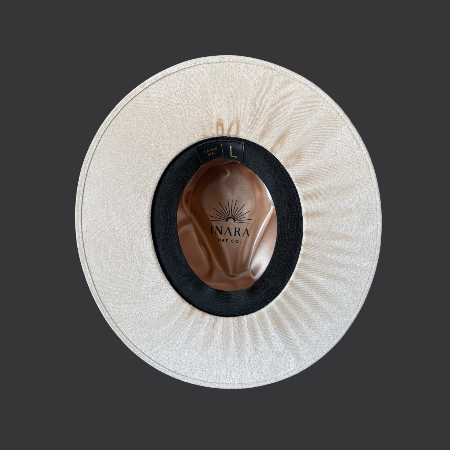 Under brim view of ivory boho fedora with black leather band, burnt orange cotton wrap, and turkey feather