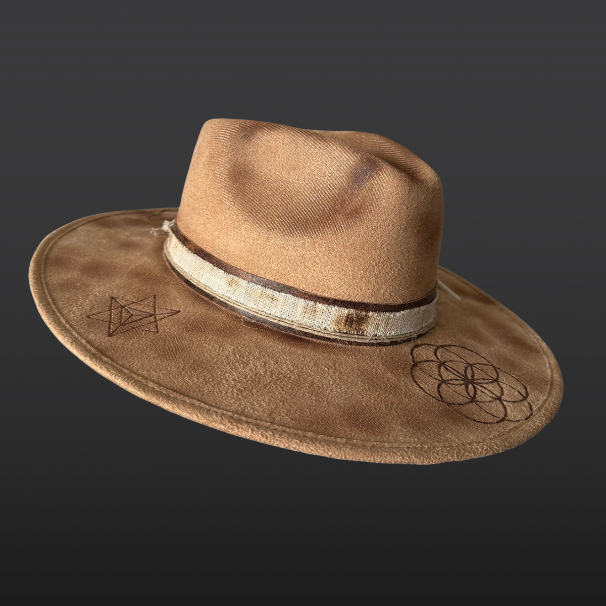 Left Side angle:
A wide-brimmed camel-colored fedora shown from the side, featuring a dark brown leather band, agate stone, turkey feather accent, and hand-burned geometric designs on the crown.