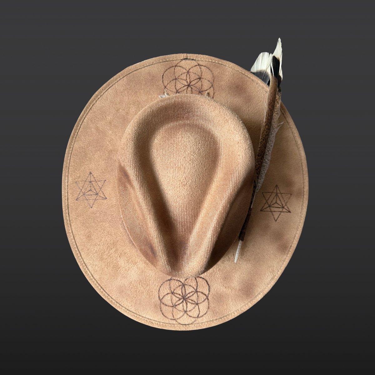 Top angle:
A wide-brimmed camel-colored fedora shown from the back, featuring a dark brown leather band, agate stone, and turkey feather accent.