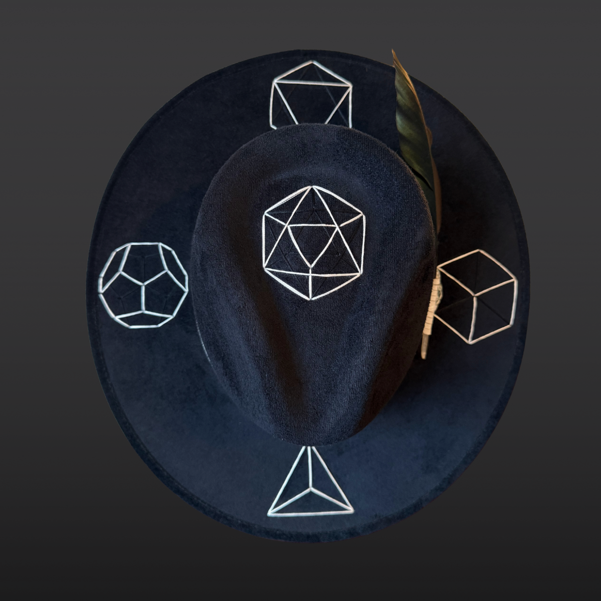 Top view:
A wide-brimmed black fedora shown from the front, featuring a white leather band and vibrant green tree agate crystal, and hand embroidered Platonic solids.