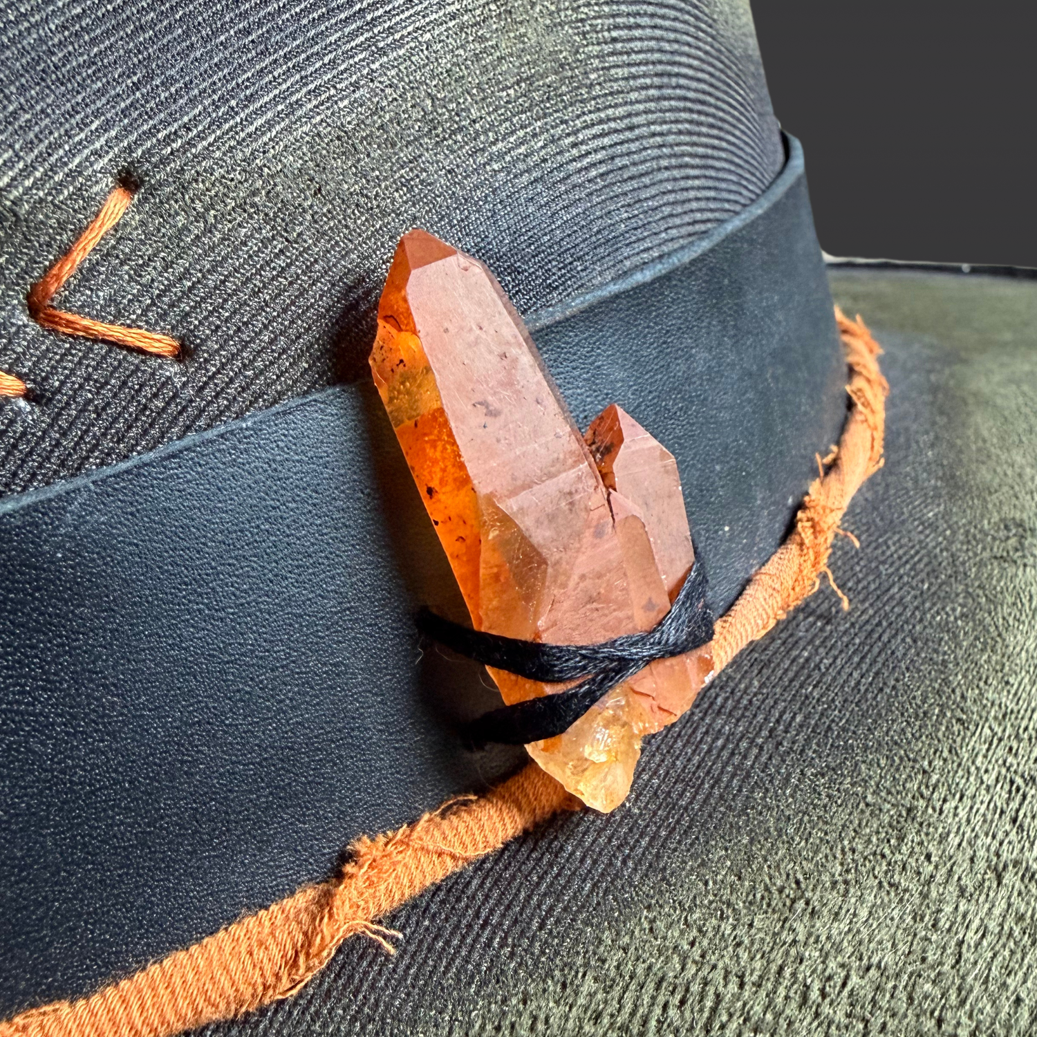 Close-up of the tangerine quartz double point crystal and orange directional arrow details on the Solar Path Fedora Hat.