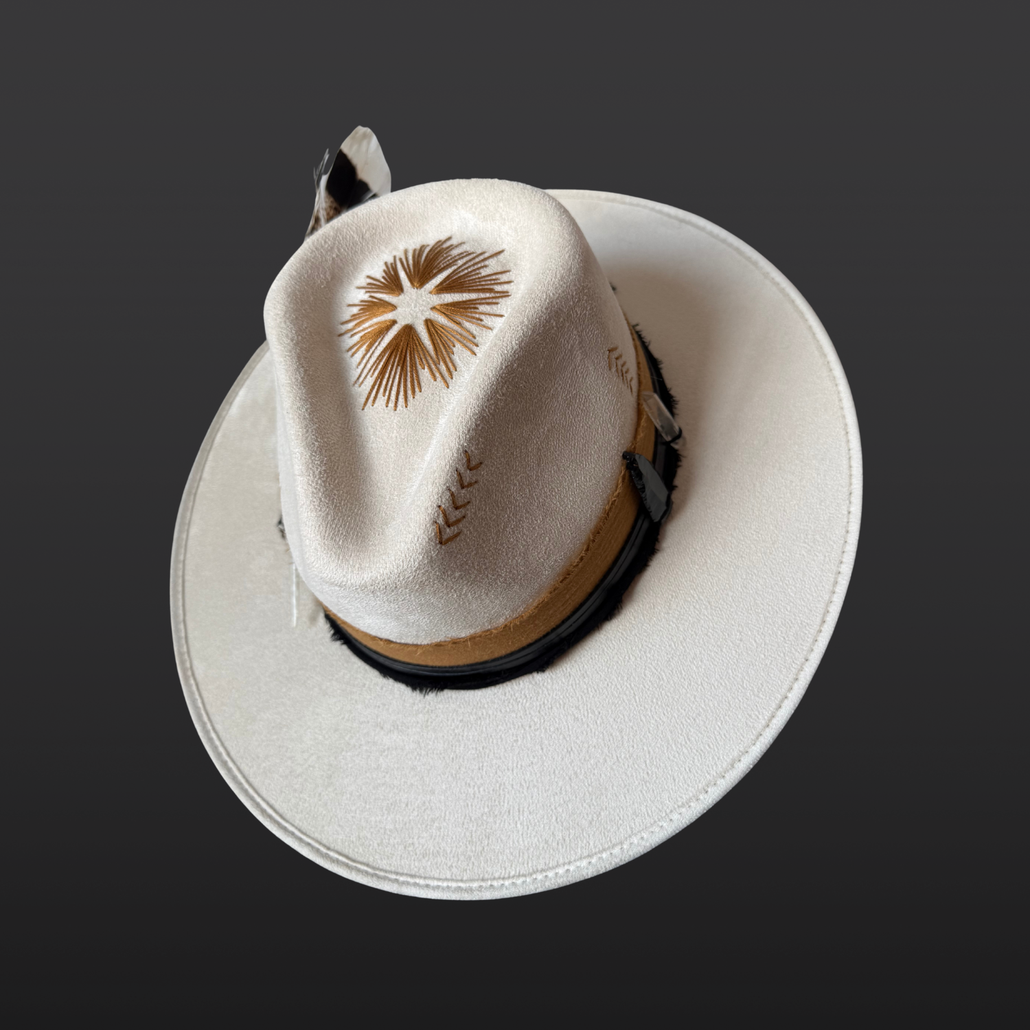 Top view of ivory wide-brim fedora hat with sunburst embroidery, Lemurian quartz, obsidian arrow, leather band and feather detail