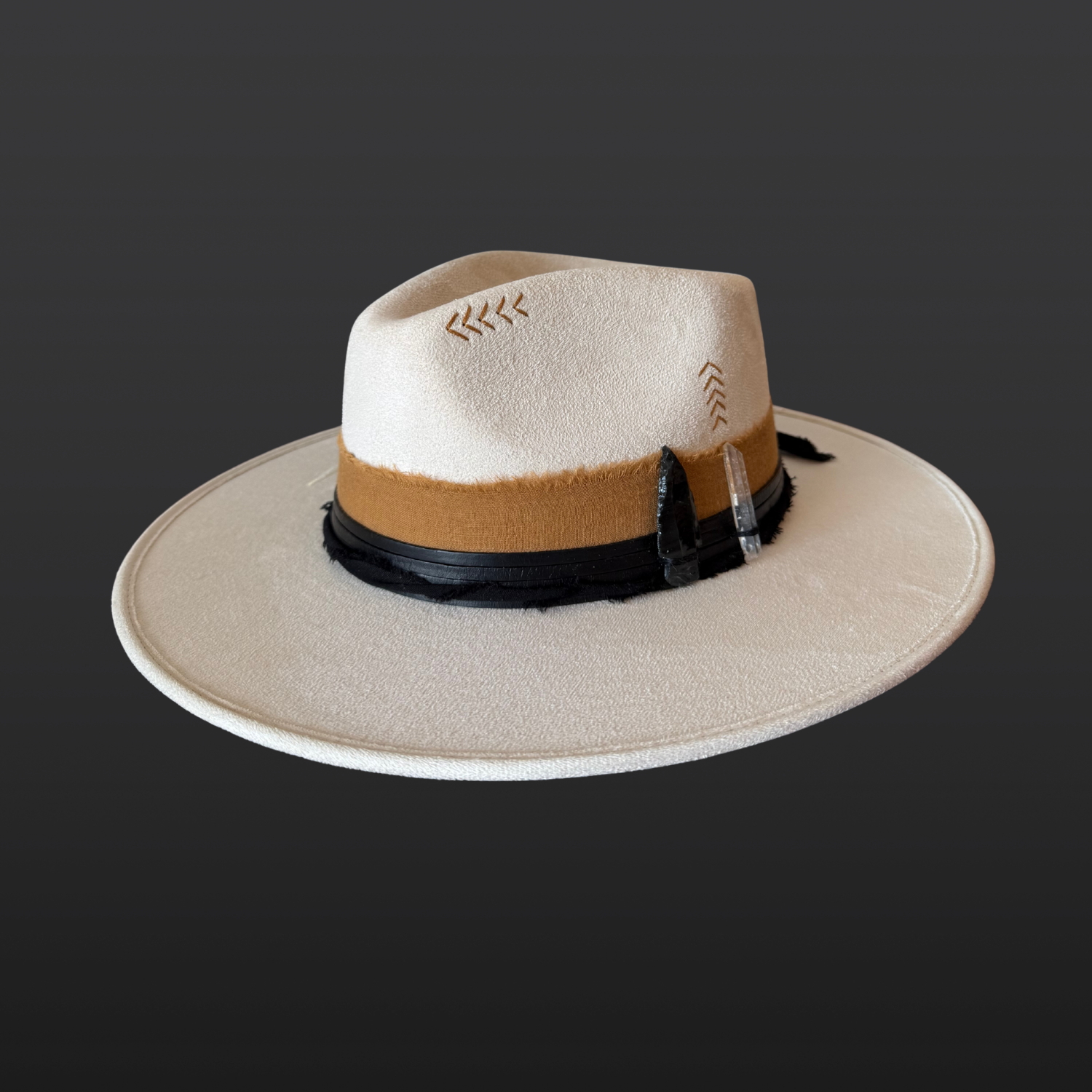 Front side view of ivory wide-brim fedora hat with sunburst embroidery, Lemurian quartz, obsidian arrow, leather band and feather detail
