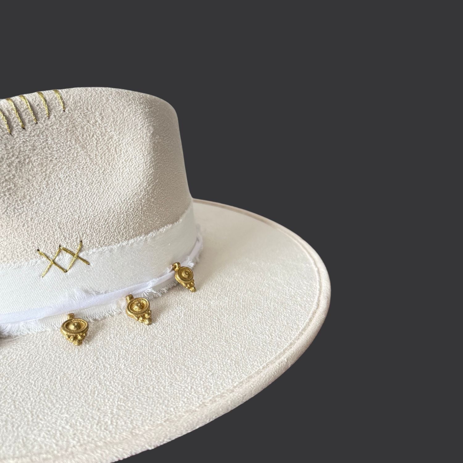 Ivory wide-brim fedora with gold hand-painted designs, white cotton band, and gold charm accents / close up 