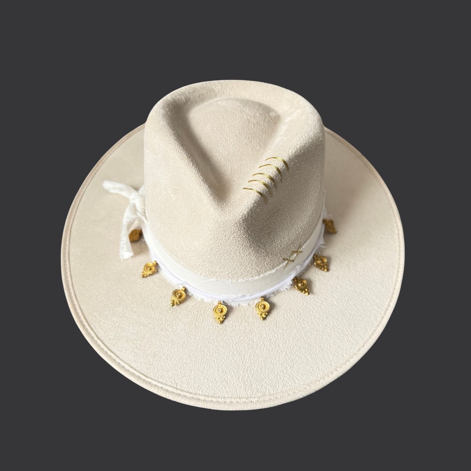 Ivory wide-brim fedora with gold hand-painted designs, white cotton band, and gold charm accents / front view