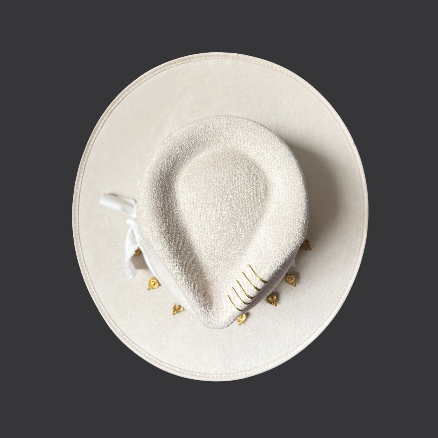 Ivory wide-brim fedora with gold hand-painted designs, white cotton band, and gold charm accents / top view