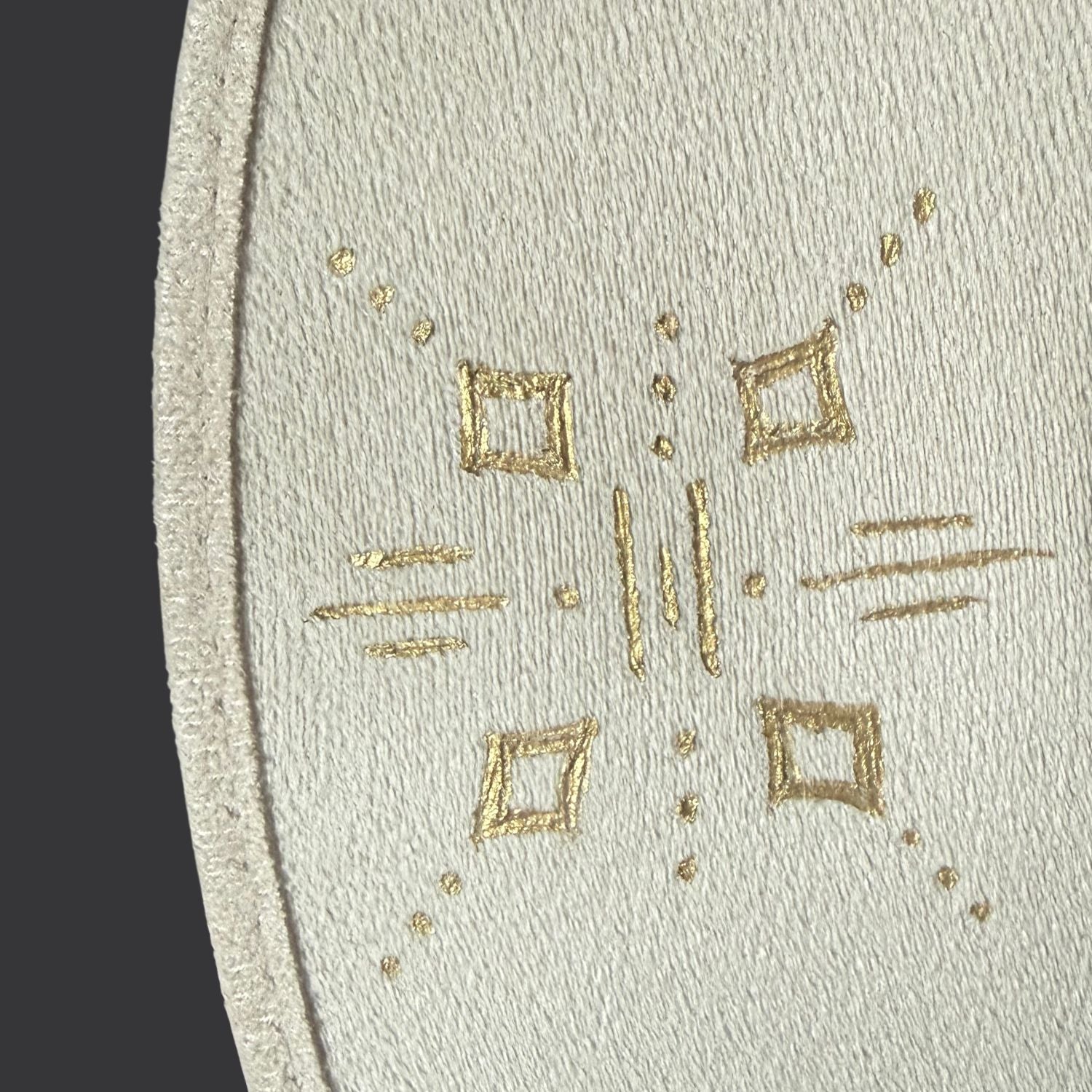 Ivory wide-brim fedora with gold hand-painted designs, white cotton band, and gold charm accents / close up of gold painted design 1
