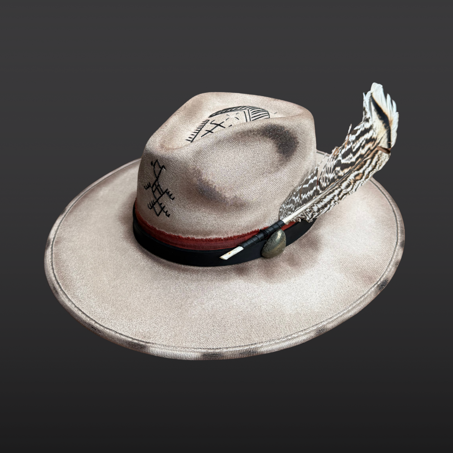 Angled view of Ember Guardian khaki fedora hat with hand-embroidered black detailing and rust red band layered with black leather.