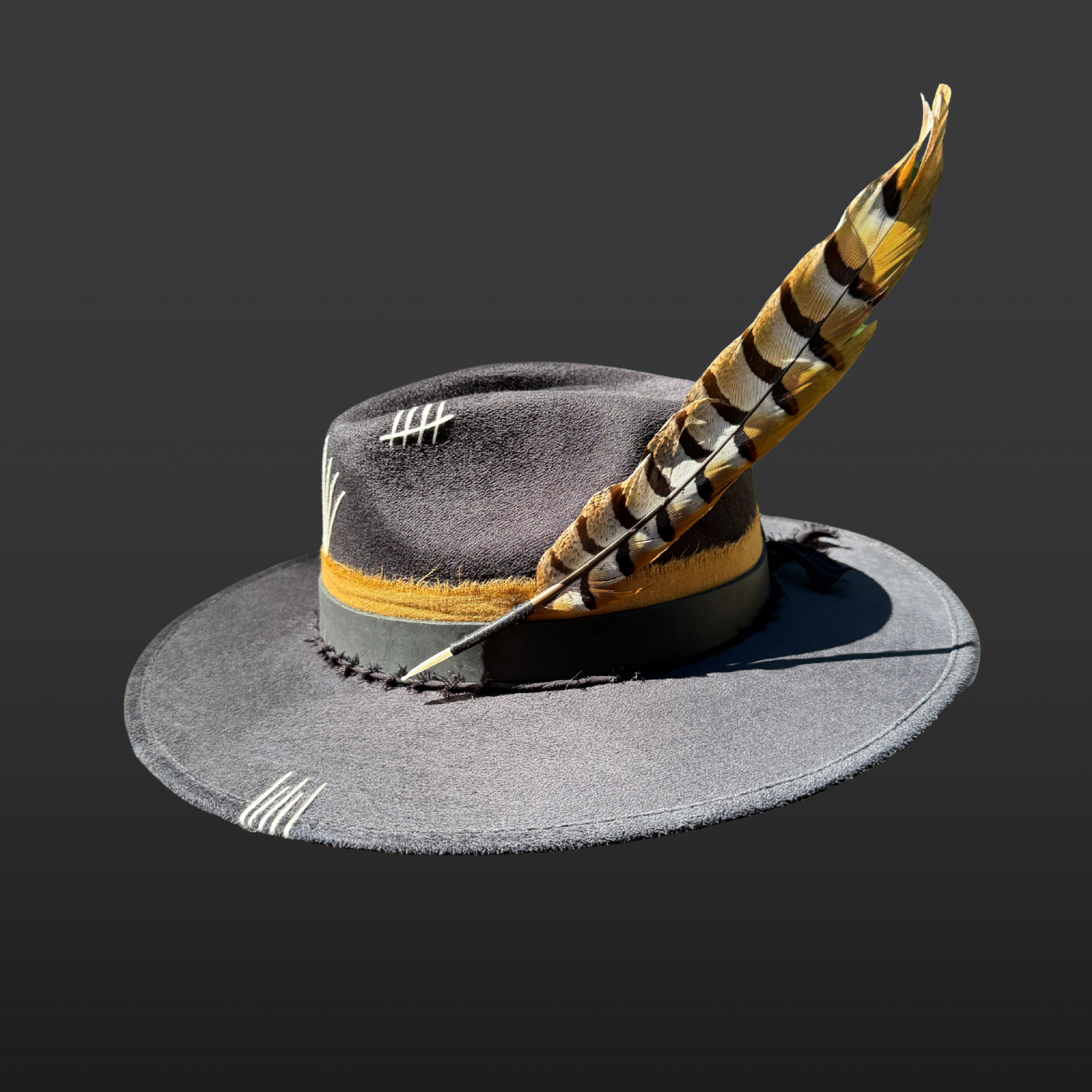Close-up of pheasant feather accent with black, brown, tobacco, and white tones attached to Wild & Free fedora.