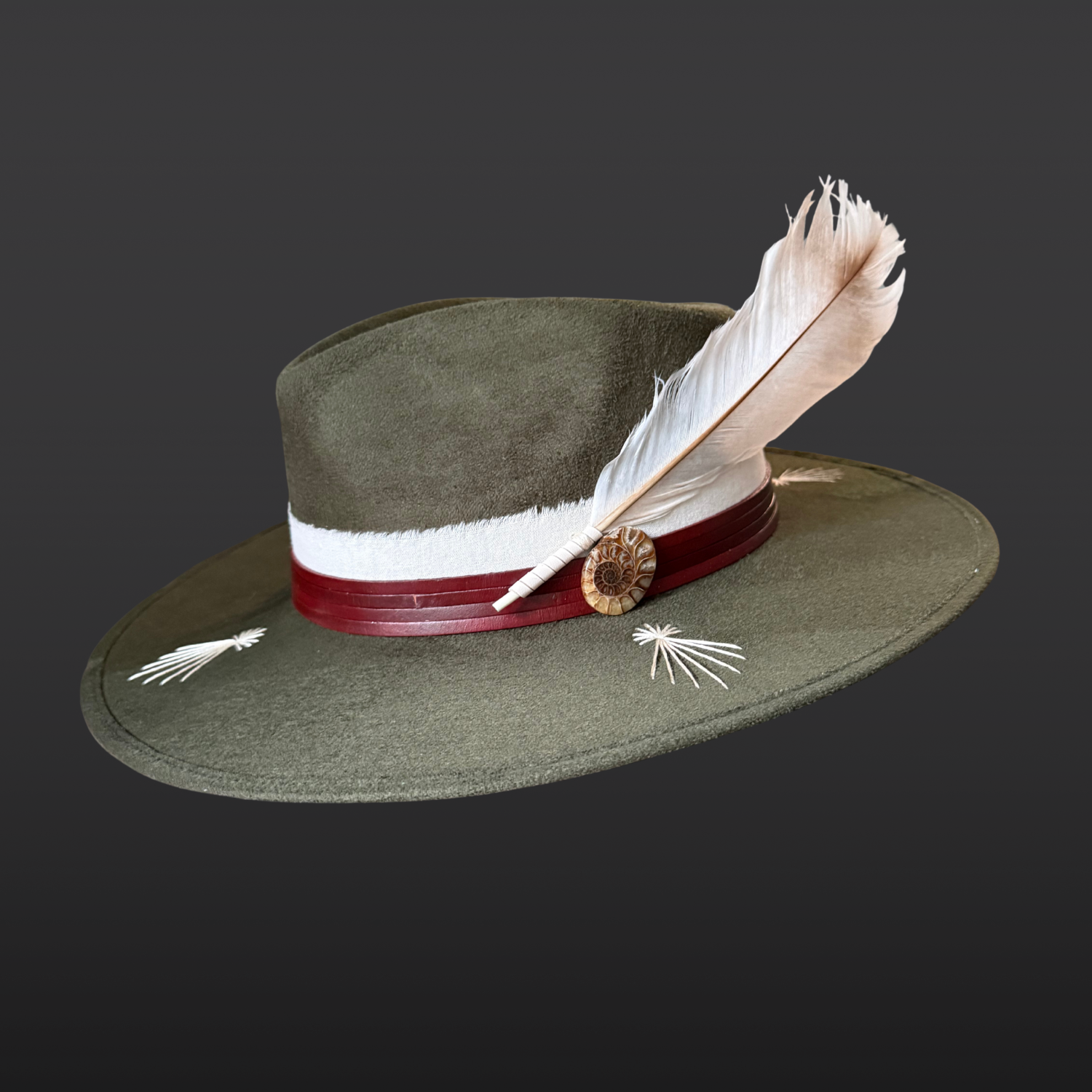 Kindred forest green fedora hat with ivory embroidered bursts, layered leather band, fossil ammonite and feather