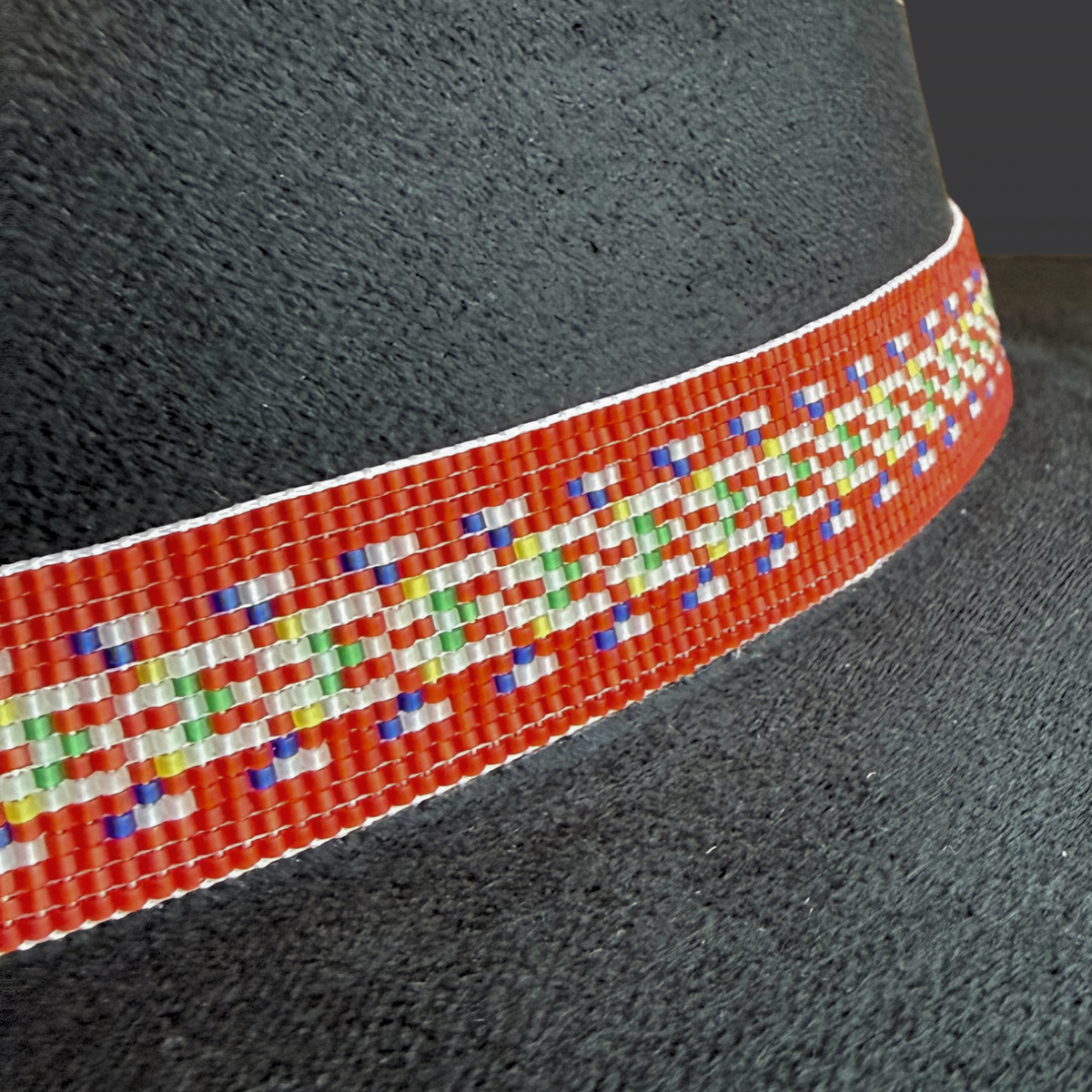 Black cordobés hat with Red River Métis beaded sash by Winnipeg Métis artist, honoring waterways, ancestry, and resilience / close up of beadwork