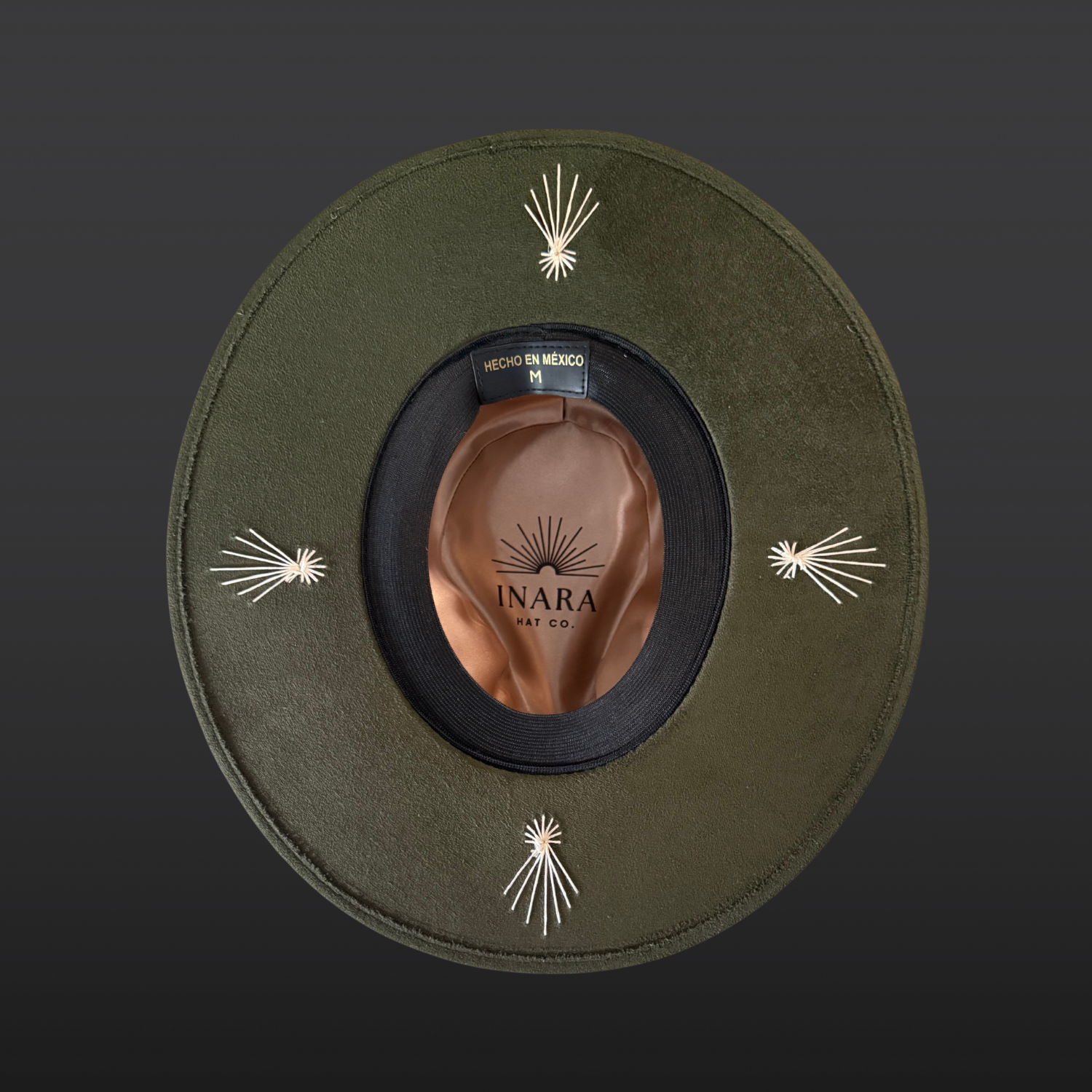 Under-brim view of the Kindred forest green fedora hat showing the ivory embroidered burst detailing