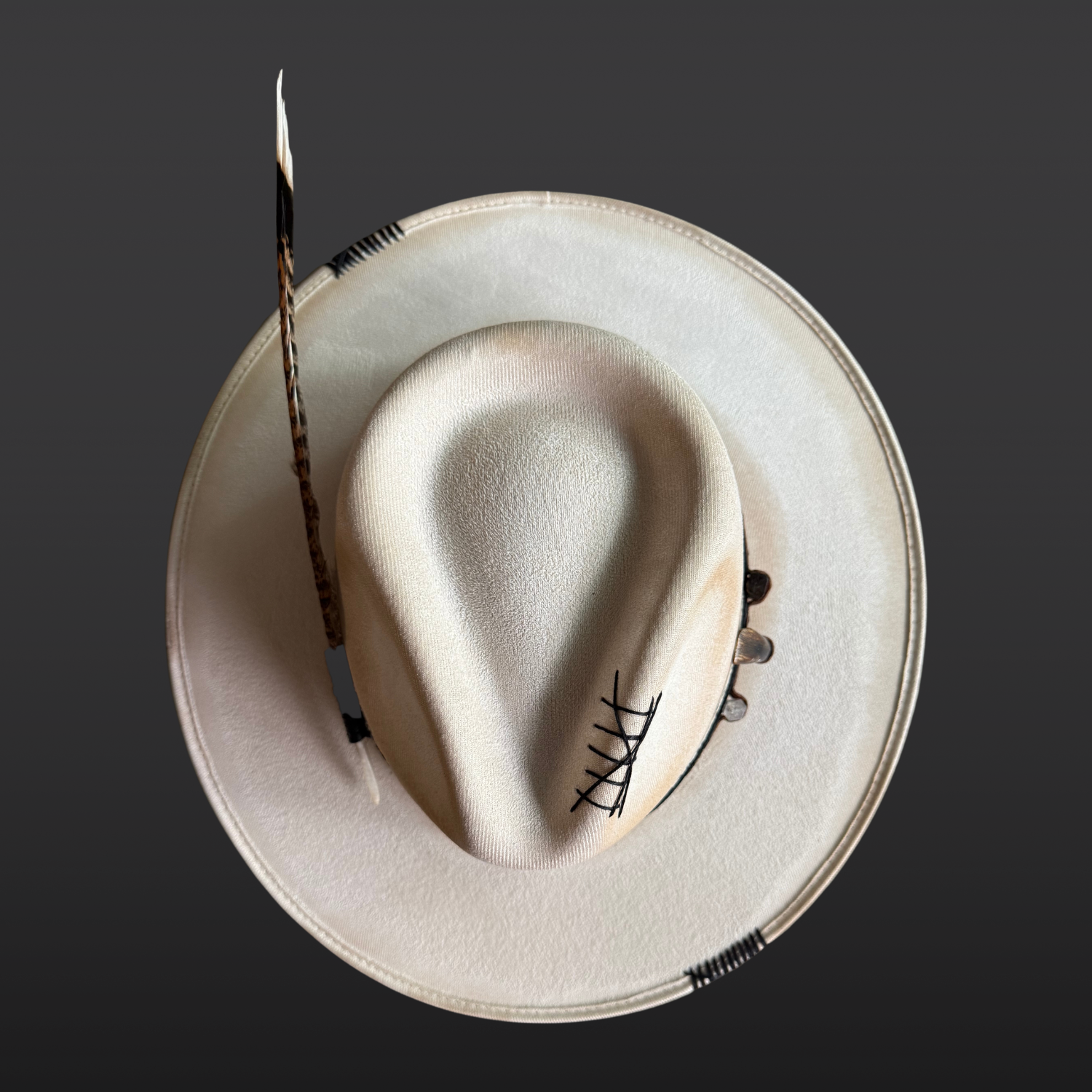 Top side view of Unbound ivory wide brim fedora hat featuring black embroidered details and a rugged hand-torched finish.