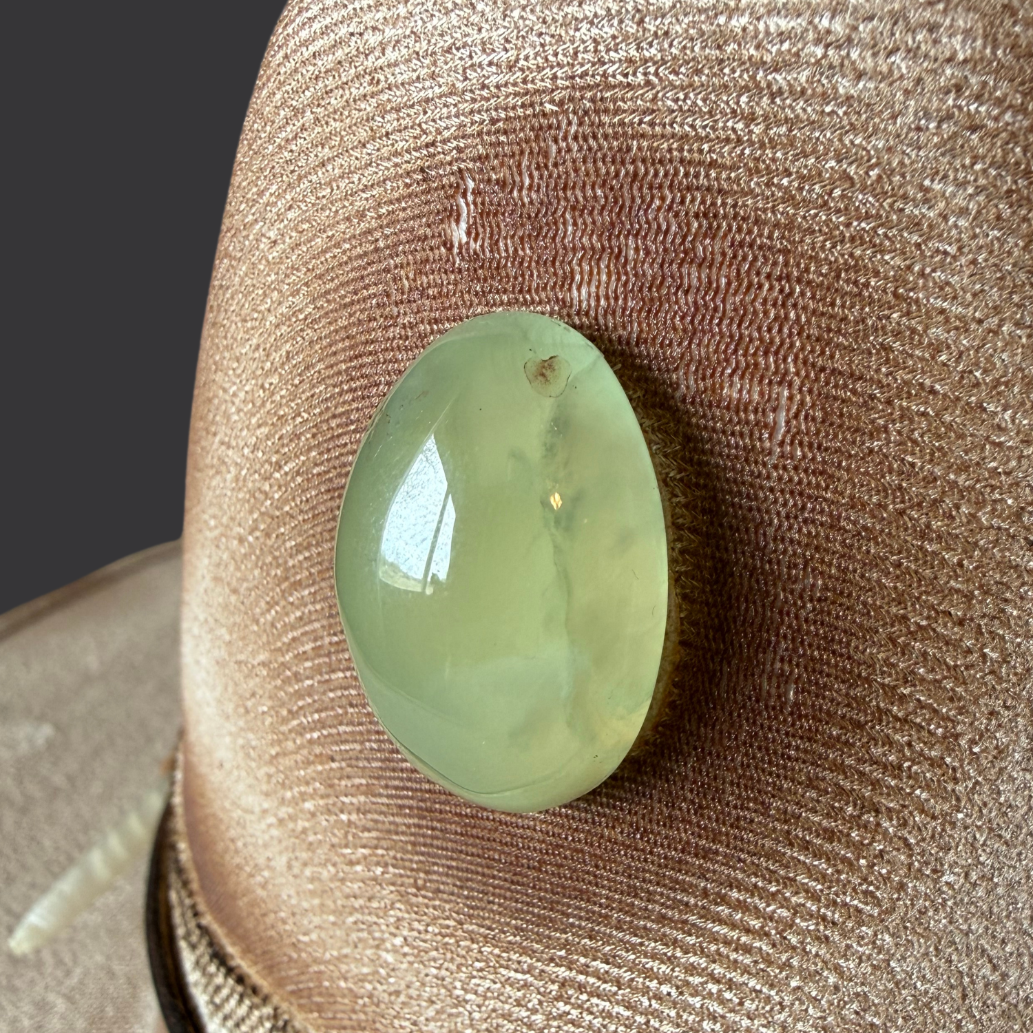 Close-up of green prehnite stone on cream fedora hat