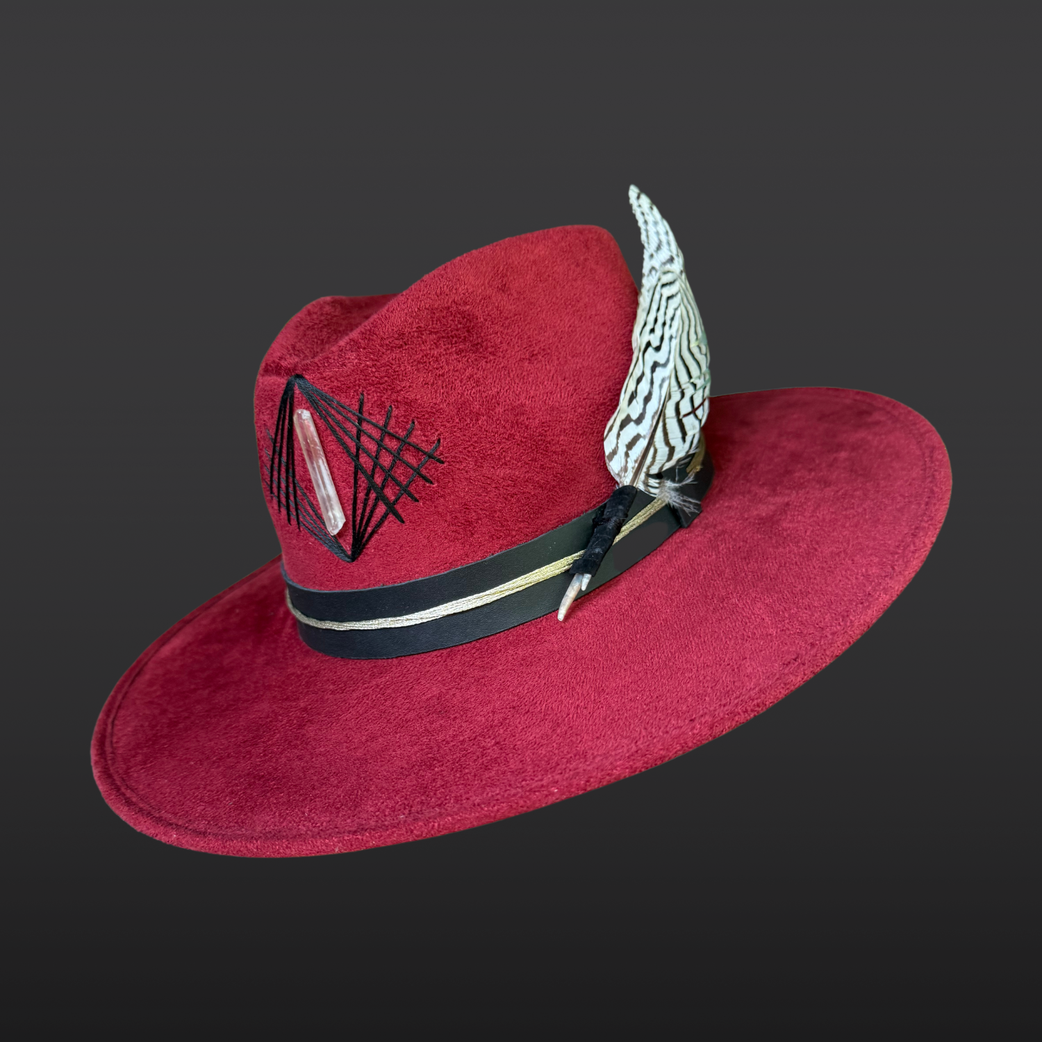 Funk It Up red wide brim fedora hat featuring hand embroidery, a clear Lemurian quartz crystal, silver pheasant feather, and black leather band with gold thread.