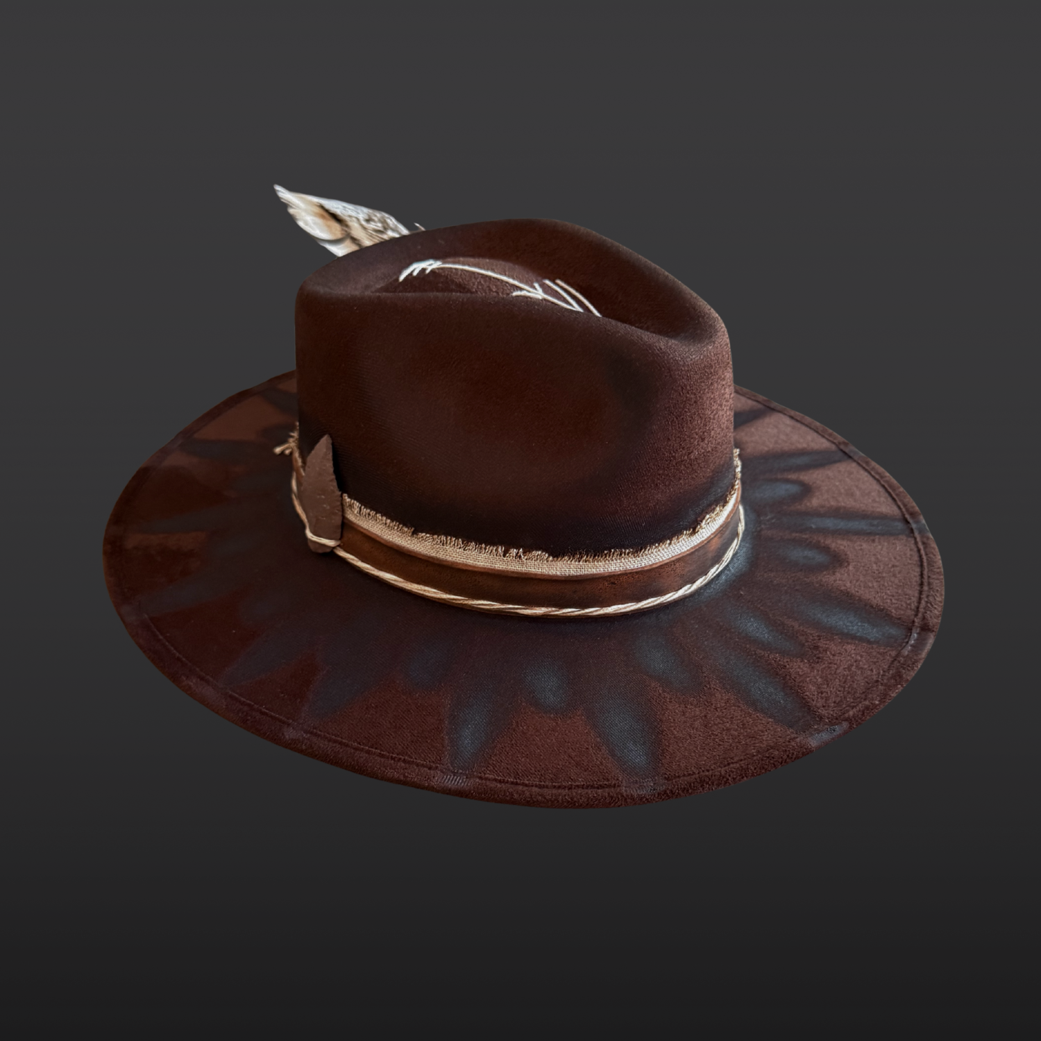 Angled Side profile of brown wide brim fedora hat showing feather embellishment, torch-burned detailing, and handcrafted boho design