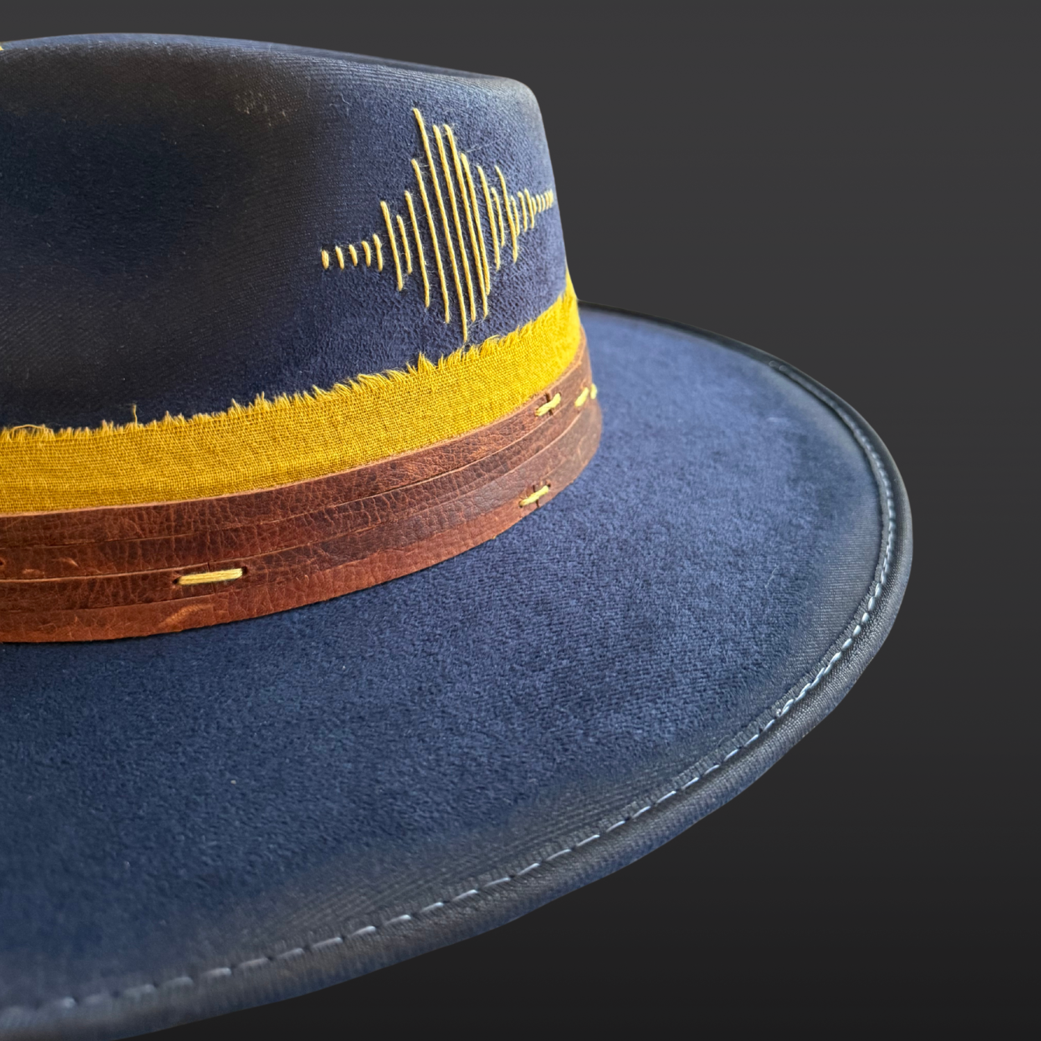 Close-up of embroidery on a navy fedora hat.