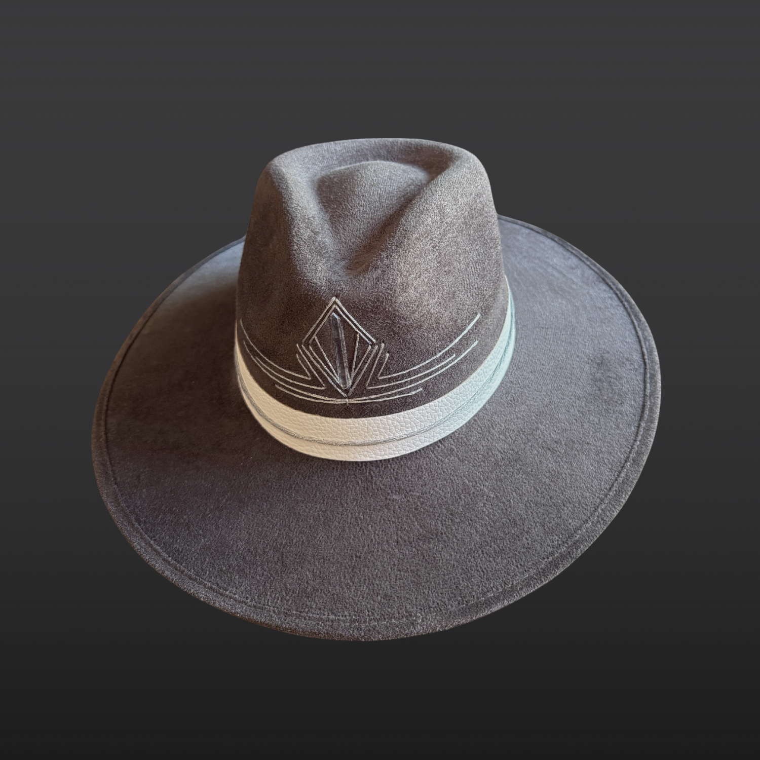 Top view of a gray statement fedora featuring a hand-embroidered silver triangle and Lemurian quartz crystal.