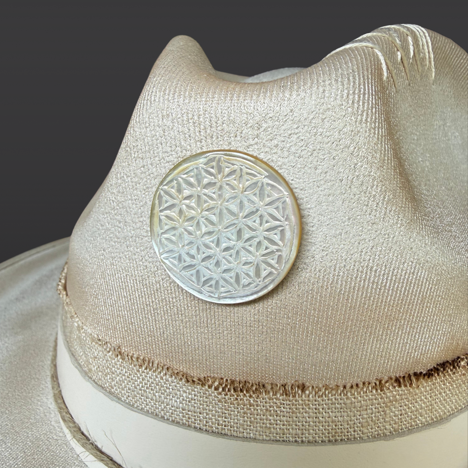 Close-up of the hand-carved Flower of Life shell centerpiece on the Ember Bloom fedora.